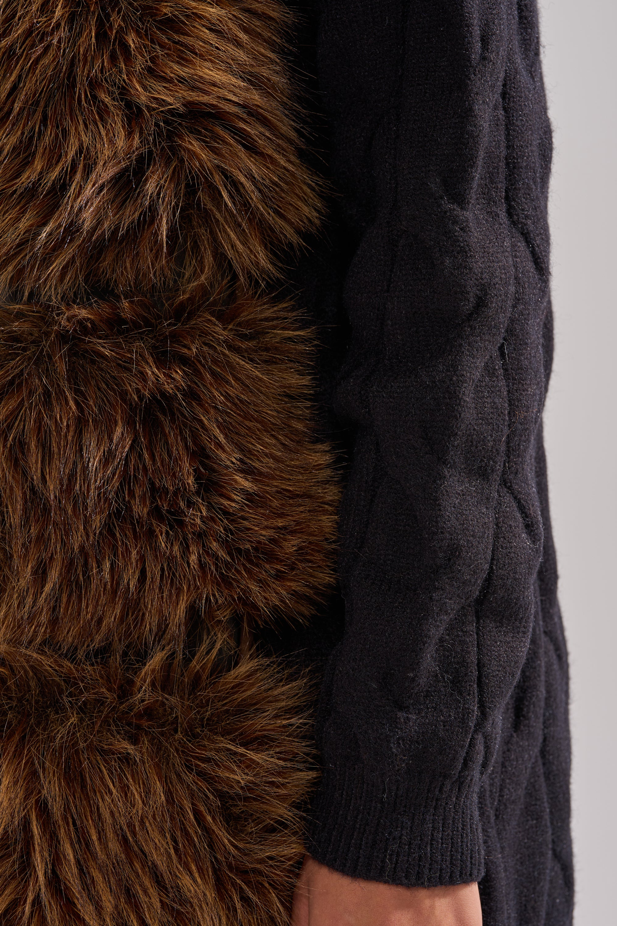 A close-up of a person wearing the WARM ME UP LONG CARDIGAN WITH FUR, highlighting the textured knit and soft fur details on the sleeve. 12