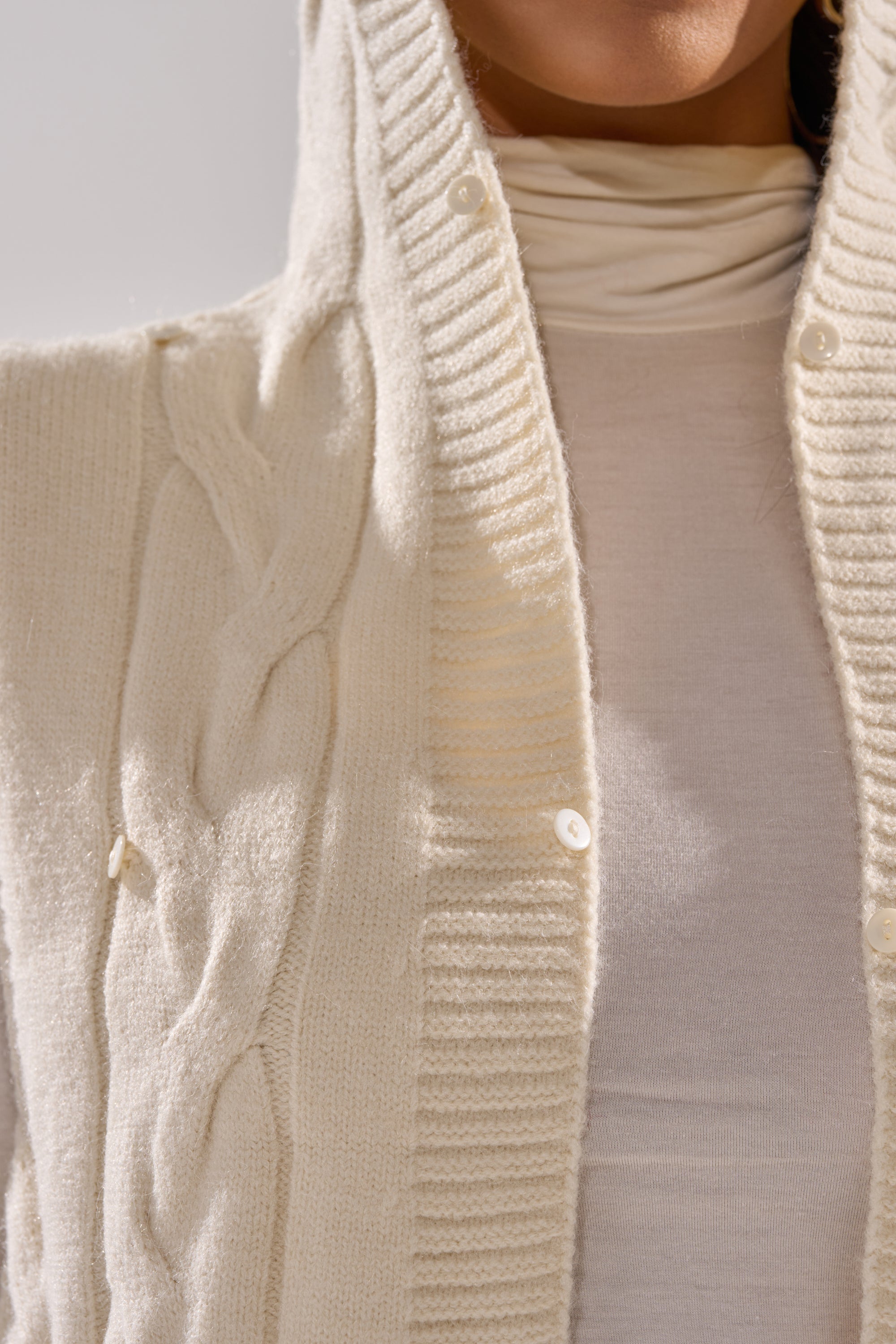 Close-up of a person wearing the LUXURIOUS FAUX FUR HOODED VEST over a matching high-neck top. The plush texture and details of this sleeveless hooded vest highlight its cozy, stylish appeal.