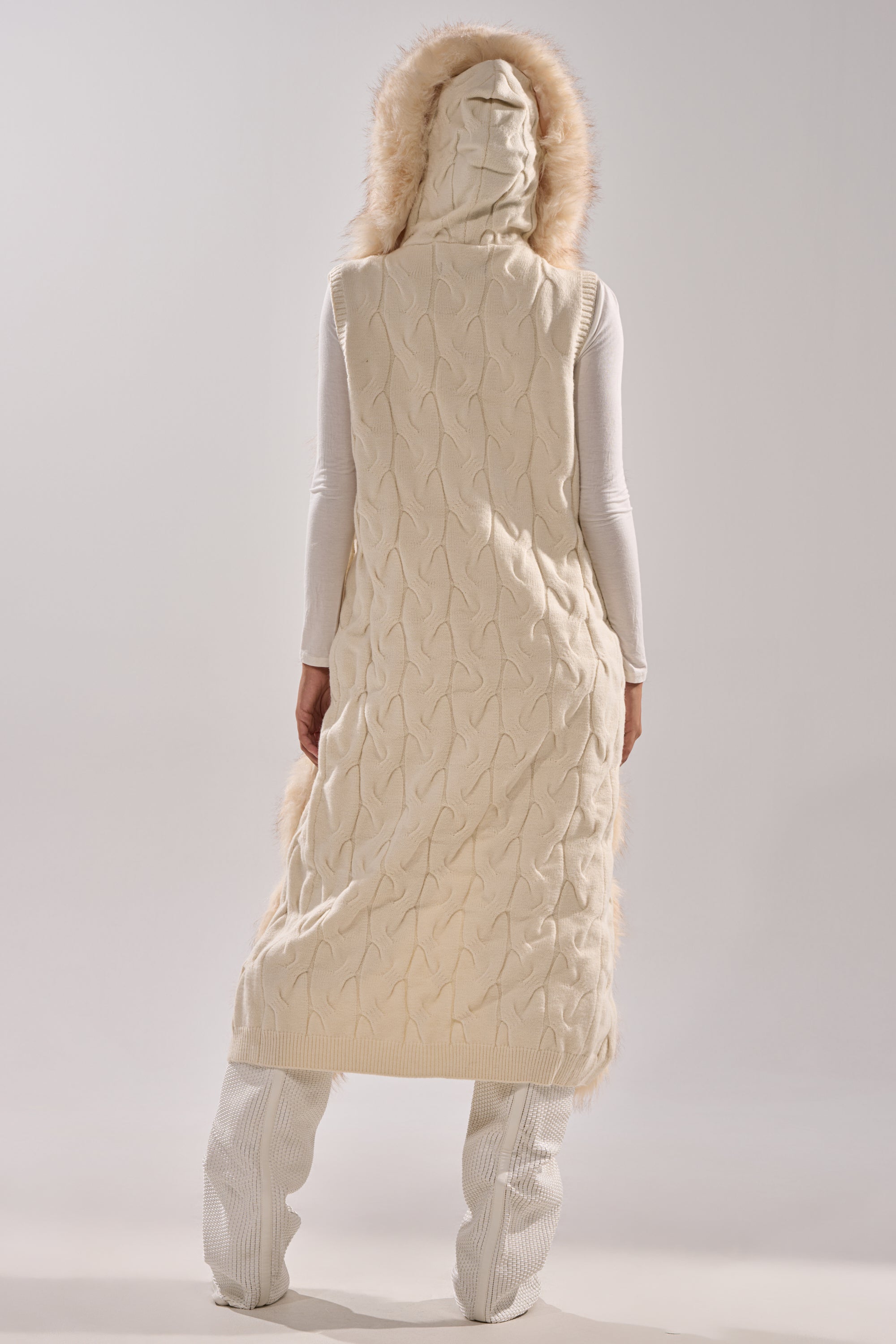 Wearing the LUXURIOUS FAUX FUR HOODED VEST over a white outfit, a person stands with their back to the camera against a plain light background.