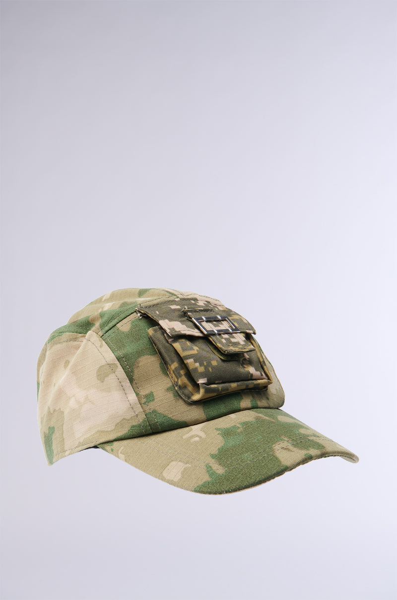Introducing the TRY AND FIND ME CAMO SNAPBACK: A stylish baseball cap featuring an adjustable Velcro strap, complete with a pixelated camo pocket on the front against a light grey background. The cap showcases various shades of green and beige in a digital camo pattern. 3