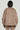 A person with short hair is seen from behind, wearing an oversized SOFIA FAUX SUEDE BOMBER and matching pants. This cozy outerwear, part of the AKIRA Label, stands out against a plain background, showcasing the luxurious texture of the outfit.