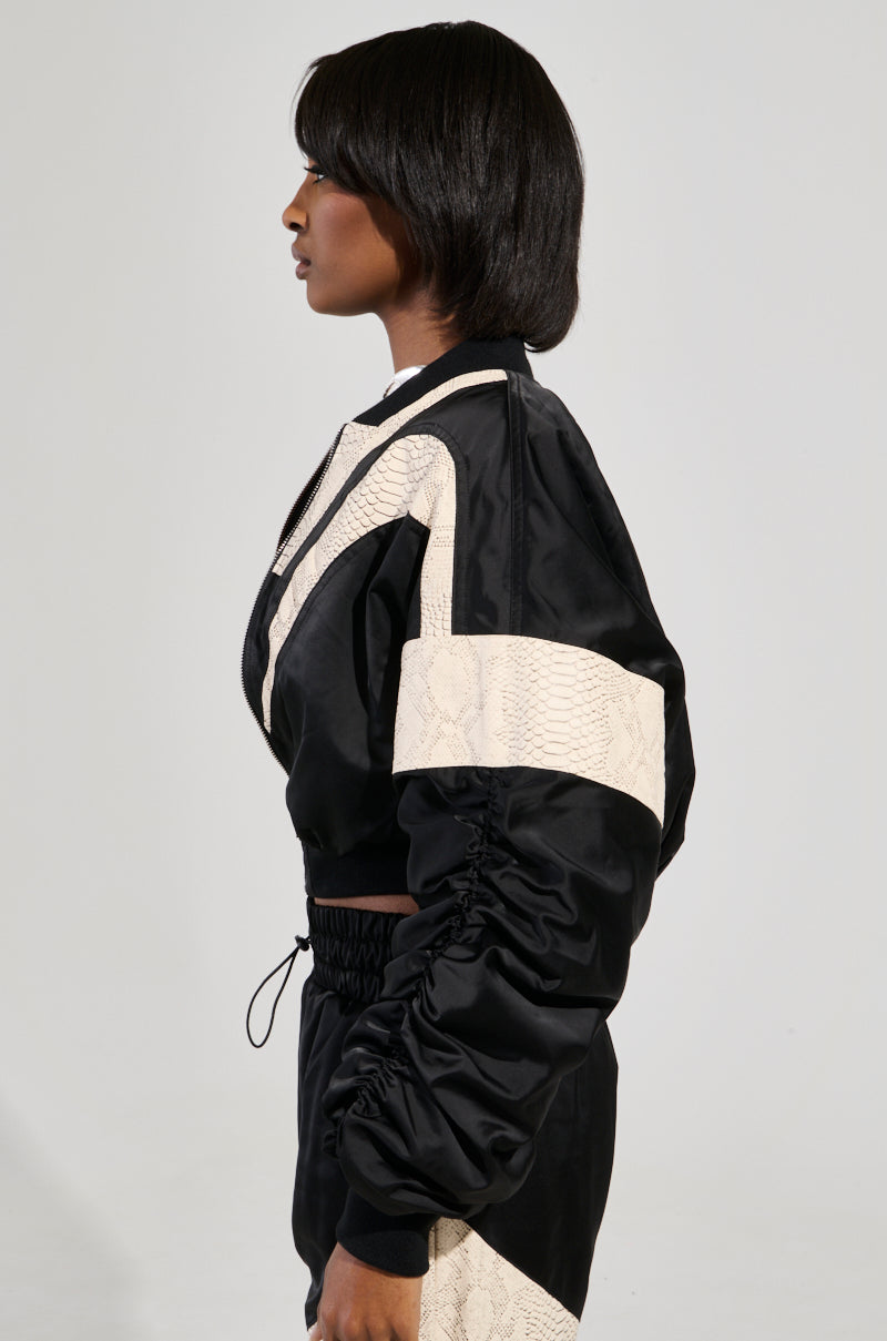 A person with short, dark hair is wearing the LAINA LIGHTWEIGHT BOMBER, a stylish tracksuit featuring color block panels on the sleeves. They are standing in profile against a plain background.