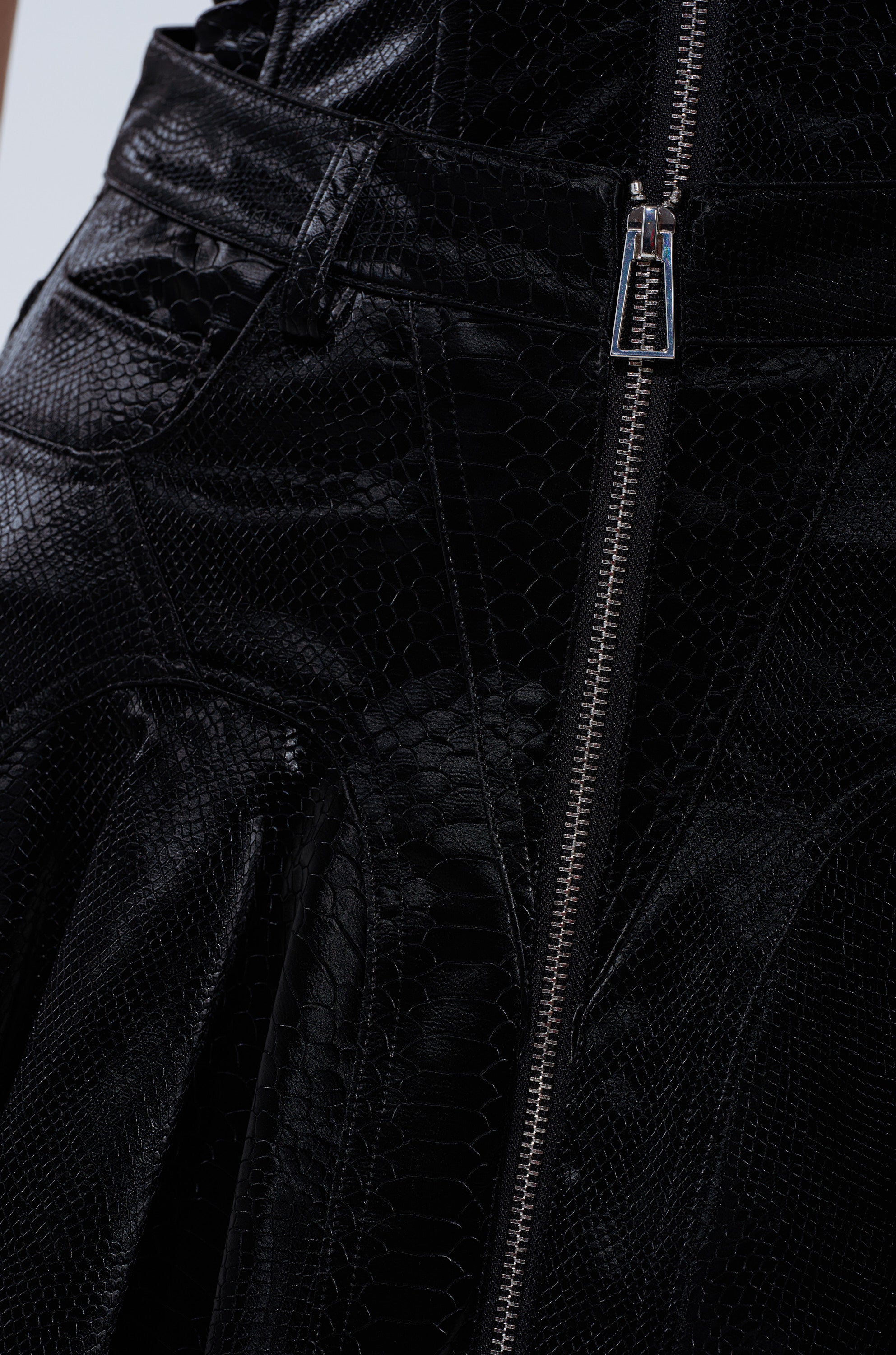 Close-up of the SWEETIE PIE MINI SKIRT in black faux snakeskin, showcasing its visible silver zipper, textured scale-like pattern, detailed stitching, and shiny finish.