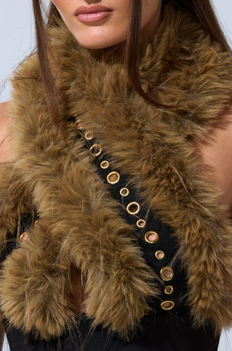 A woman wears the WILD AND FREE FUR BLOUSE—a soft, brown faux fur wrap over a black top with gold-tone details. Only her lower face, neck, and shoulders are visible, highlighting the blouse's elegant drape and rich texture. 11