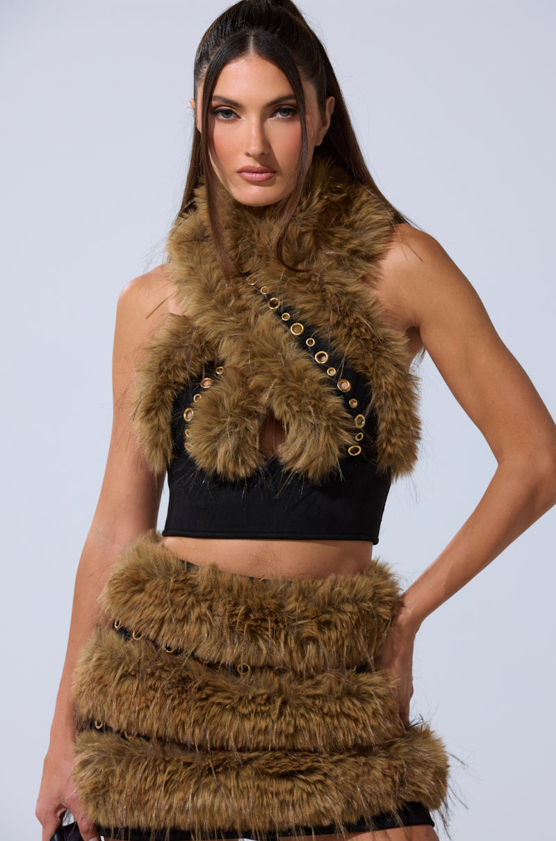 A woman confidently poses against a plain light background, wearing the WILD AND FREE FUR BLOUSE paired with a black skirt and featuring gold-tone grommet detailing. 3