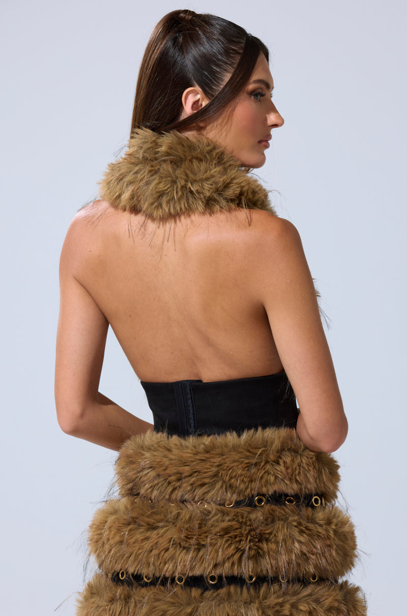 A woman with long dark hair in a high ponytail is seen from the back, wearing the WILD AND FREE FUR BLOUSE, a strapless black top with brown faux fur trim around the neck and tiered detailing. The background is light gray. 5