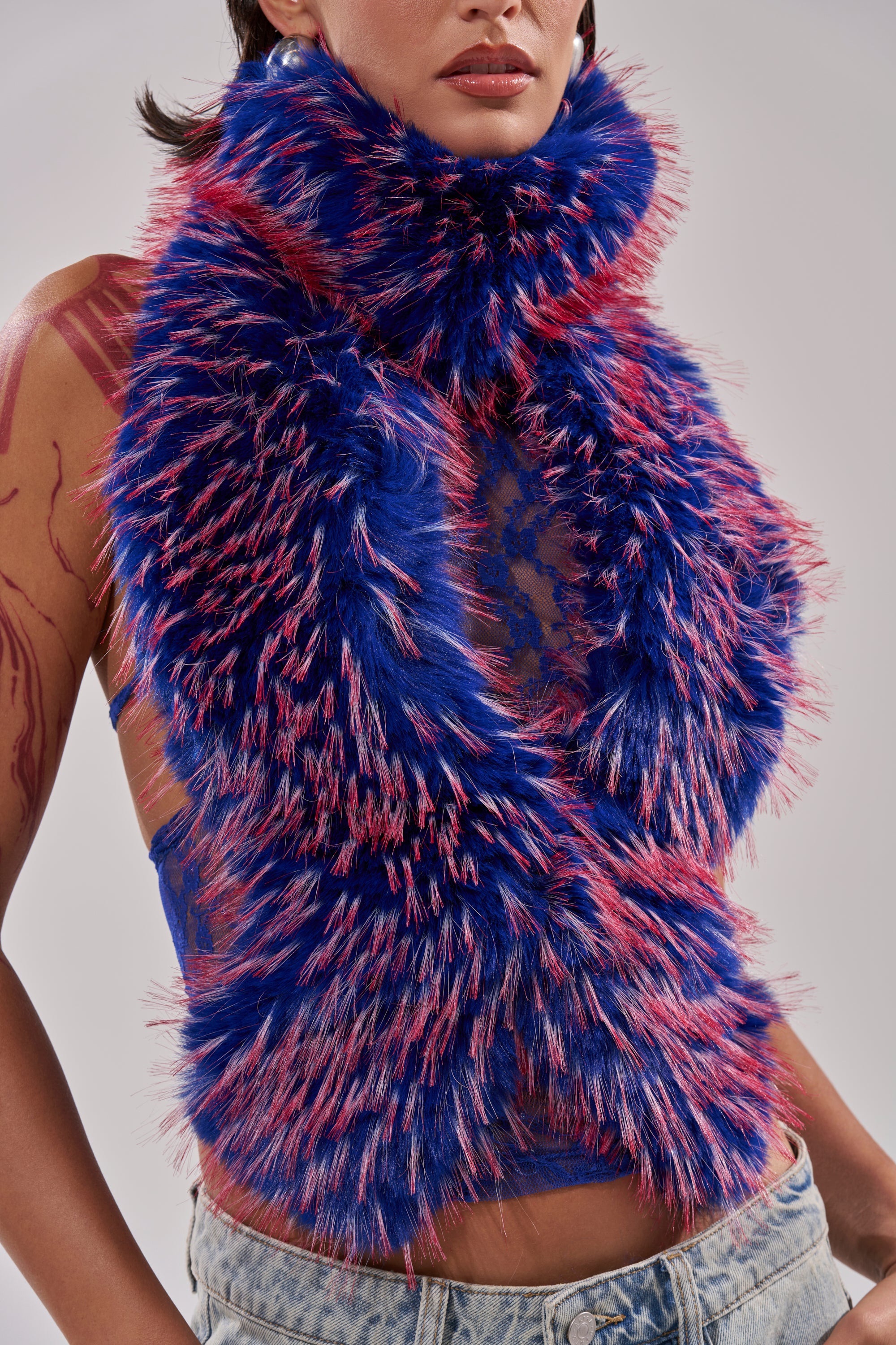 A person wears a blue and pink faux fur scarf, sheer blue lace top, and light blue jeans. The fluffy accessory layers over the FEEL ME BABY FUR BLOUSE IN BLUE, with only their lower face and torso visible. 8