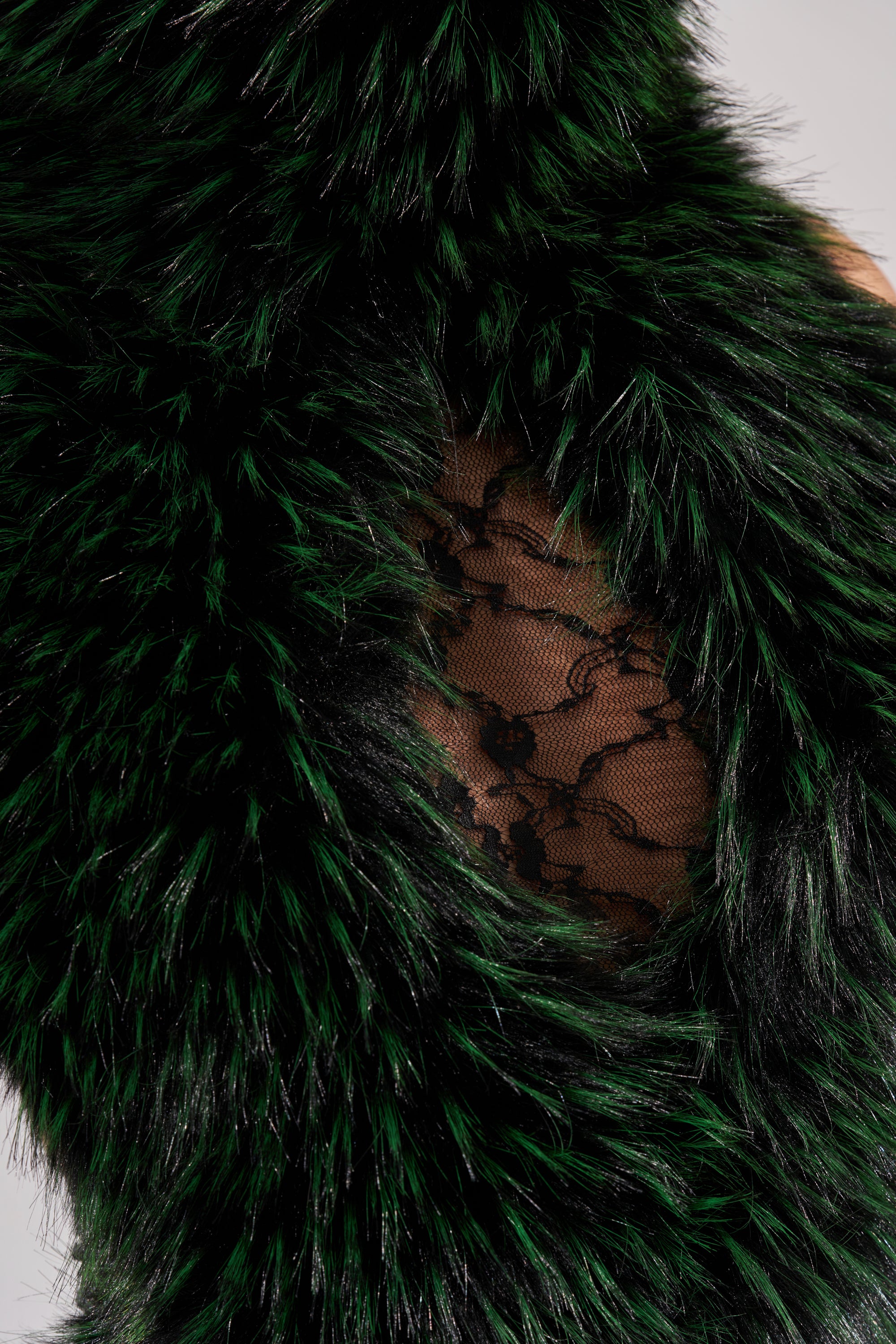 Close-up of the FEEL ME BABY FUR BLOUSE, featuring deep green faux fur framing black floral lace that subtly reveals skin.