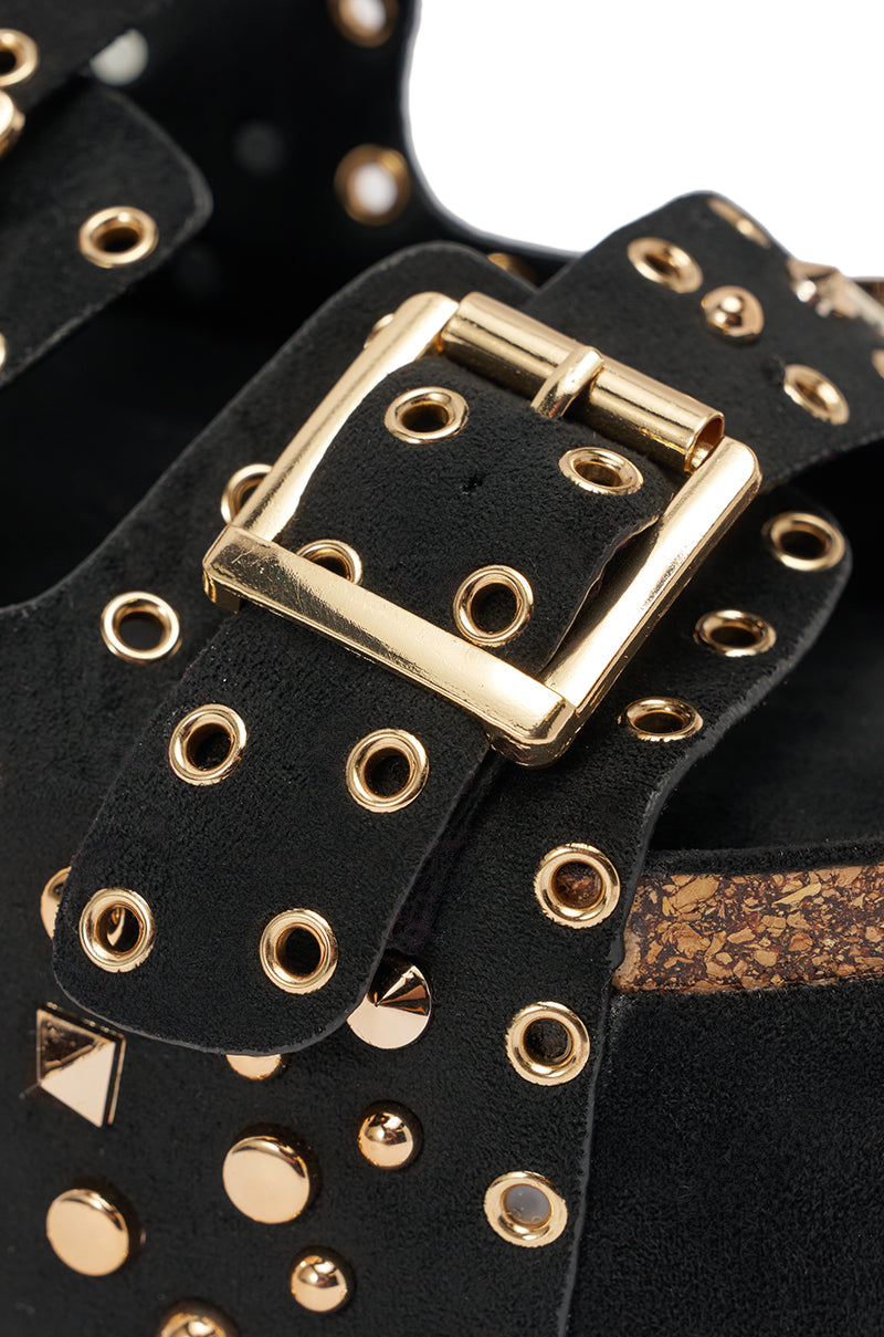 Close-up of the AZALEA WANG KAEGAN BLACK FLATFORM STUD EMBELLISHED SLIP ON SANDAL, highlighting its black suede strap with gold studs, eyelets, shiny gold buckle, and cork-textured side detail under the strap. 6