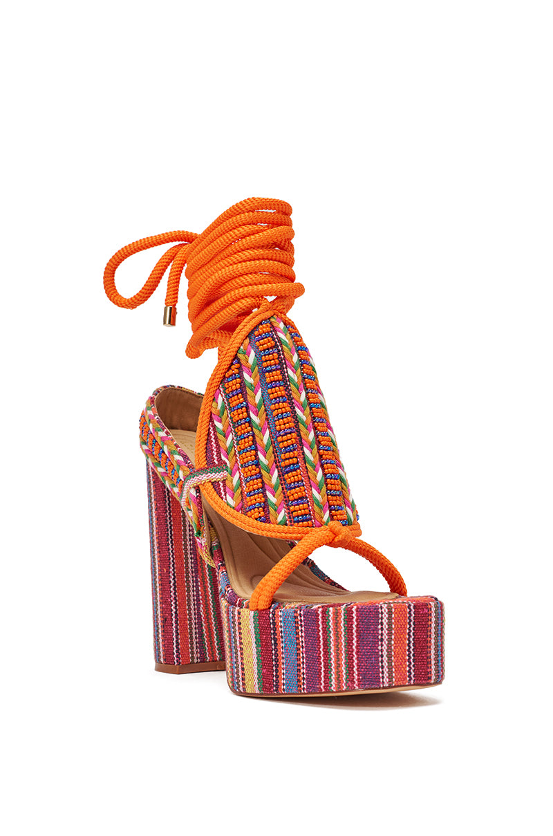 The AKIRA GOLD KALINA MULTI CHUNKY BEADED SANDAL features a vibrant boho design with a striped multicolor heel, intricate woven straps, and thick orange laces that wrap around the ankle. 5