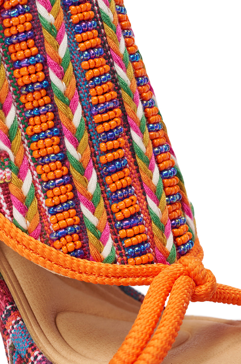 Close-up of the AKIRA GOLD KALINA MULTI CHUNKY BEADED SANDAL, featuring colorful orange braided laces, intricate beading in orange, green, pink, blue, and white on beige footbed. 7