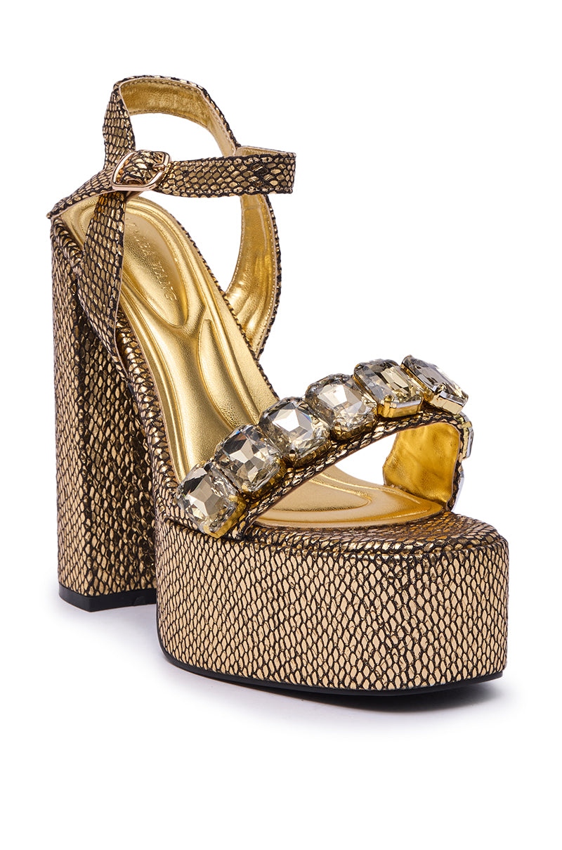 The AZALEA WANG KAMILLA Gold Rhinestone Sandal showcases a textured snakeskin-style pattern, thick platform sole, chunky heel, ankle strap, and bold clear gemstone accents on the front strap.