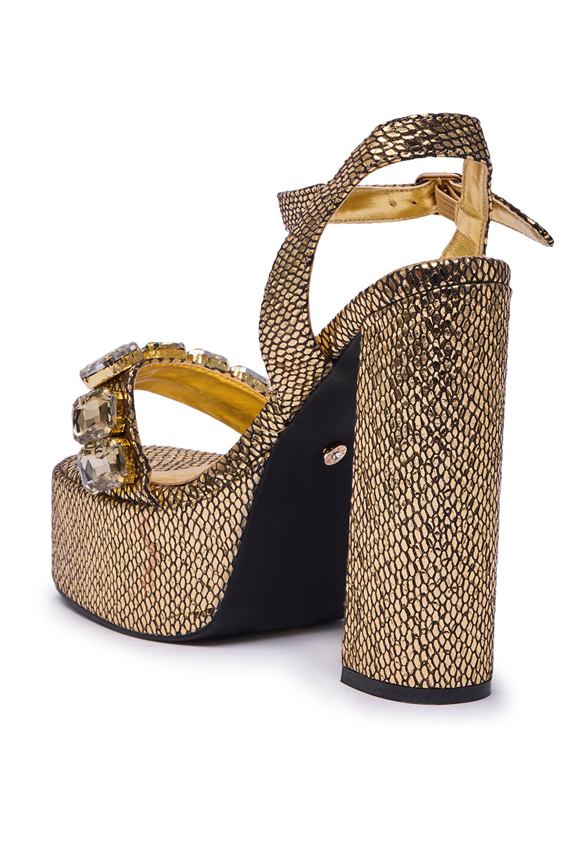 The AZALEA WANG KAMILLA GOLD RHINESTONE SANDAL features a snakeskin-textured gold platform sole, thick straps, chunky heel, large jewel embellishments on the front, gold inner lining, and black sole.
