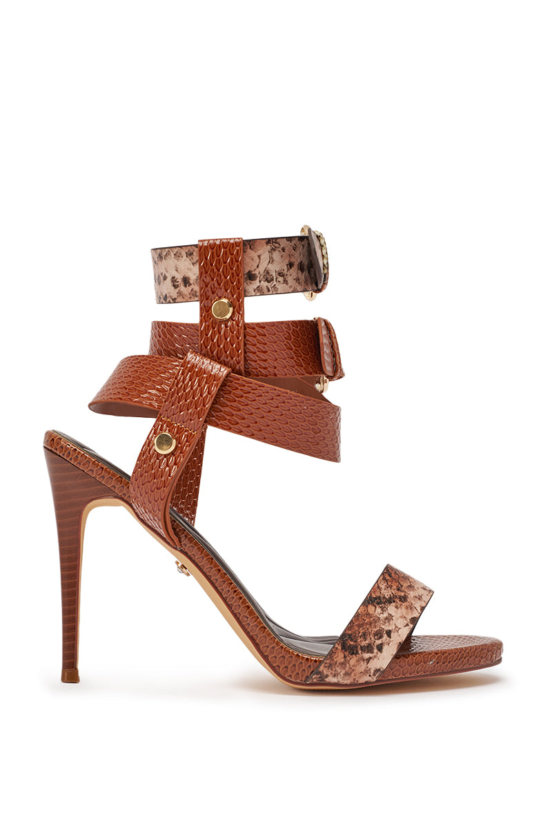 The AKIRA GOLD KADINSKY COGNAC MULTI SNAKE MATERIAL STILETTO SANDAL features ankle-wrap buckle straps, gold accents, and a comfort cushion insole, displayed in a side view against a white background. 4