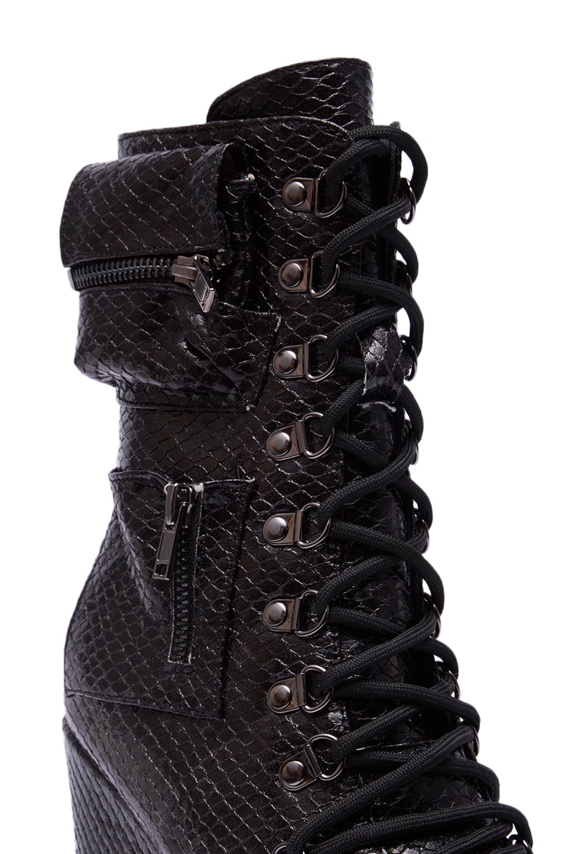Close-up of the AZALEA WANG KAPULE BLACK SNAKE PLATFORM BOOTIE, featuring snakeskin texture, metal eyelets, black laces, a wedge heel, and two small zippered side pockets.