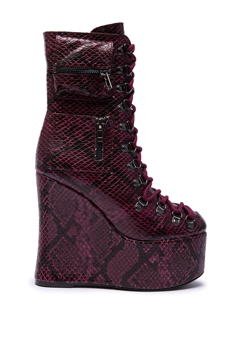 The AZALEA WANG KAPULE BURGUNDY SNAKE PLATFORM BOOTIE features a stylish maroon and black snakeskin pattern, high wedge heel, front lace-up design, and side zipper details.