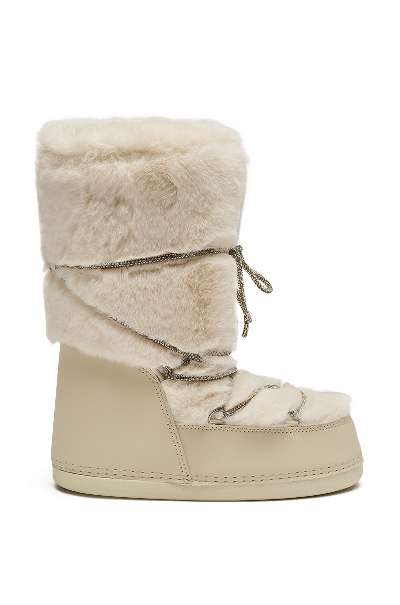 The AZALEA WANG KARMELA CREAM FUR MOON BOOT boasts a plush high cream faux fur shaft with matching wraparound laces, a thick sole, and a smooth lower section for cozy style and warmth.