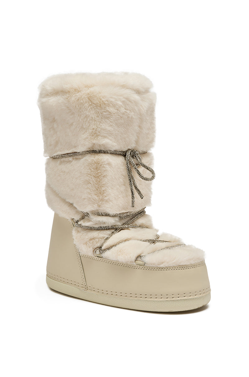 The AZALEA WANG KARMELA CREAM FUR MOON BOOT is a beige faux fur winter boot with a thick, furry upper, metallic laces, rounded toe, and flat sole.