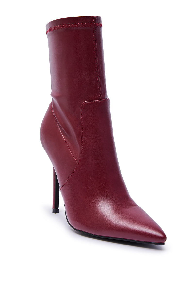 The AZALEA WANG KATHII BURGUNDY BOOTIE features smooth dark red faux leather, a pointed toe, and a slim stiletto heel, displayed against a white background.