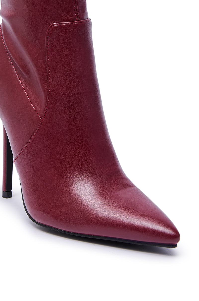 The AZALEA WANG KATHII BURGUNDY BOOTIE features a sharply angled pointed toe and slender stiletto heel, crafted from smooth faux leather, shown in both side and front views.