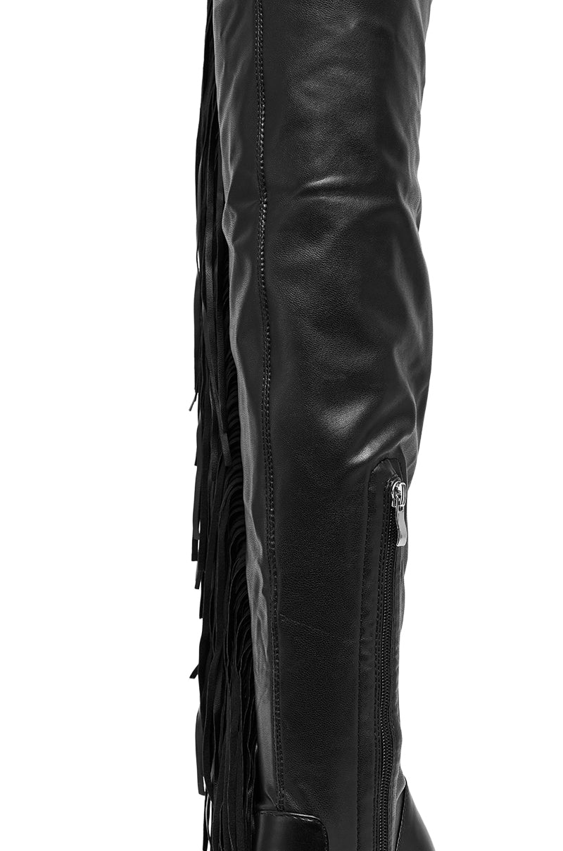 Close-up of the AZALEA WANG KATRICIA BLACK FRINGE CHUNKY BOOT in black vegan leather, featuring a visible zipper and long fringe detail along the outer side. 6