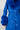 A person models the NEW KAYA FUR LINED TRENCH IN BLUE, showcasing its vibrant faux leather finish accentuated with plush faux fur trim on the collar and cuffs. This coat, complete with buttons and an adjustable belt, is set against a plain white background.