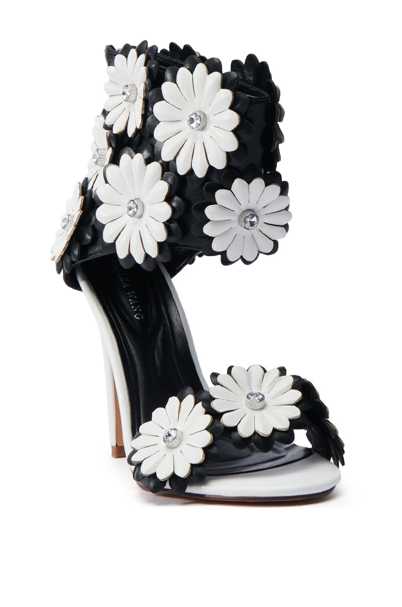 The AZALEA WANG KAYDE Black & White Stiletto Sandal is a chic vegan faux leather shoe, embellished with 3D floral appliques and rhinestone centers. It features a black base and white sole and heel for a bold, elegant design.