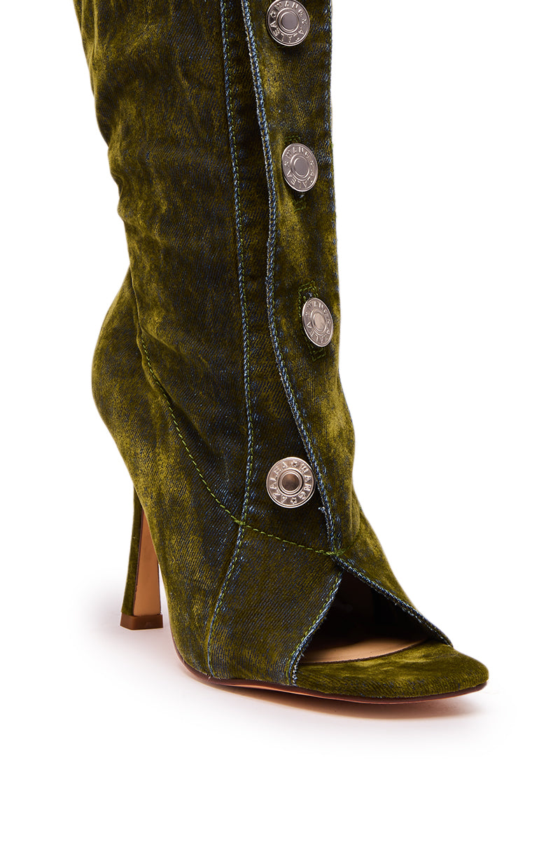 A close-up of the AZALEA WANG KAZUKI OLIVE SLOUCHY DENIM BOOT, featuring high heels, an open toe, olive green velvet-like fabric, blue stitching, and large metallic side buttons.