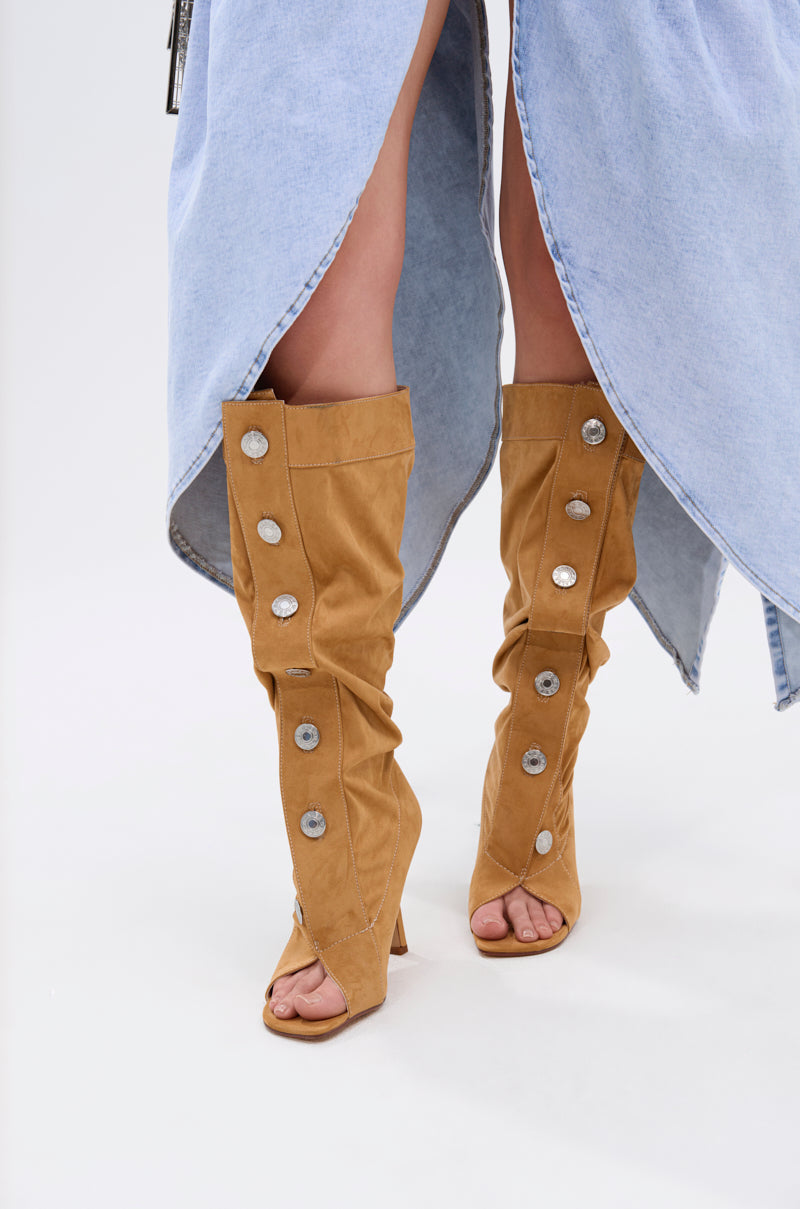 Styled with a light denim skirt with an asymmetrical, knee-revealing hem, the AZALEA WANG KAZUKI TAN SLOUCHY SUEDE OPEN TOE BOOT features stiletto heels, large silver buttons, and luxe faux suede construction.