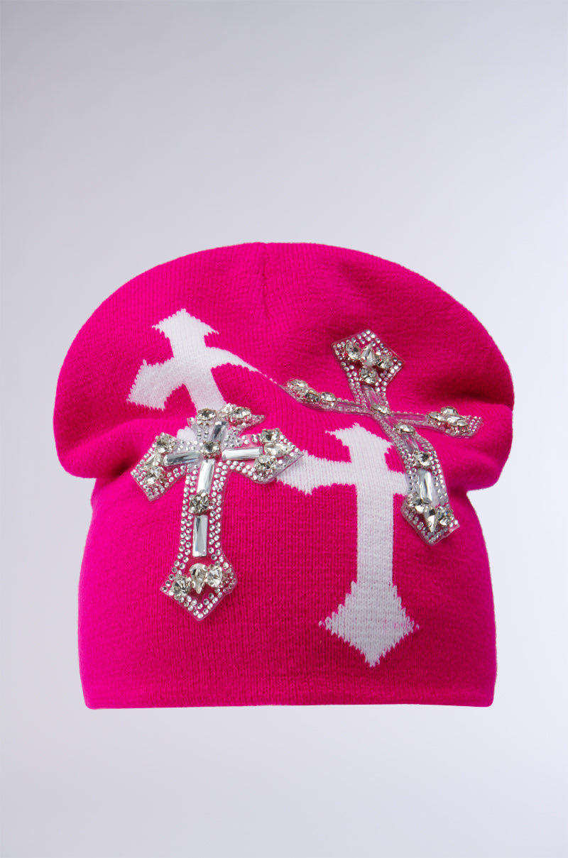 The CROSS LOVE BEANIE is a pink beanie featuring two prominent, religiously-inspired crosses and decorative silver rhinestones, set against a plain, light-colored background that highlights its elegant appeal. 1