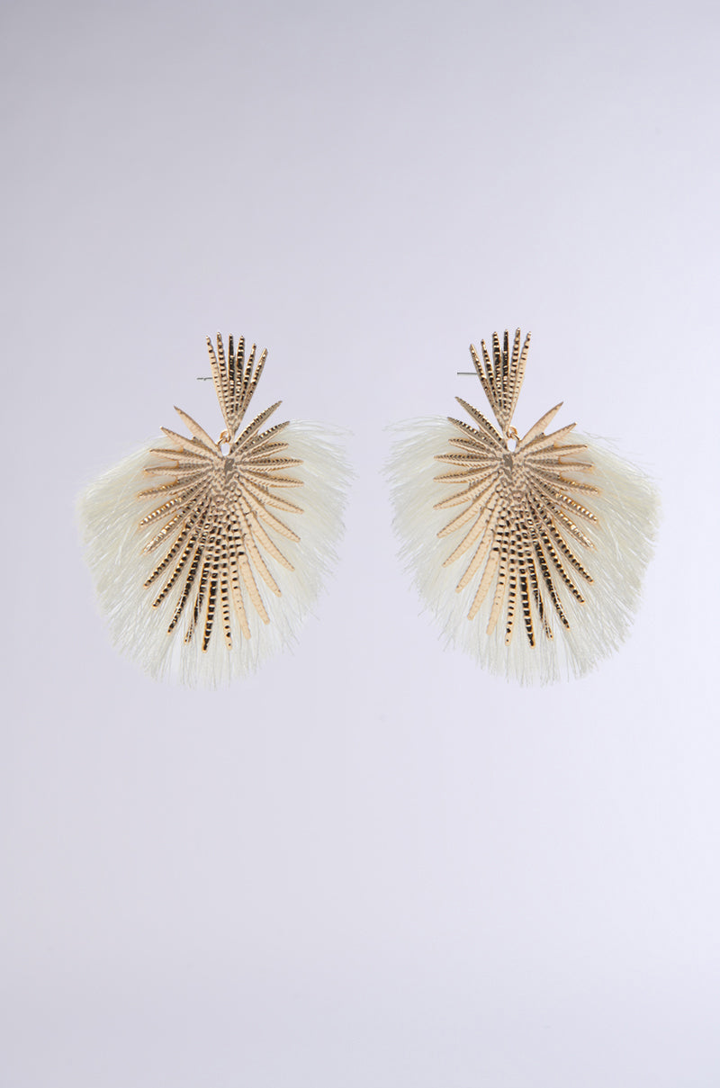 The TULUM EARRING features a gold fan shape with intricate cutout patterns and white thread fringes, perfect for resort glamour, shown against a plain light gray background. 2