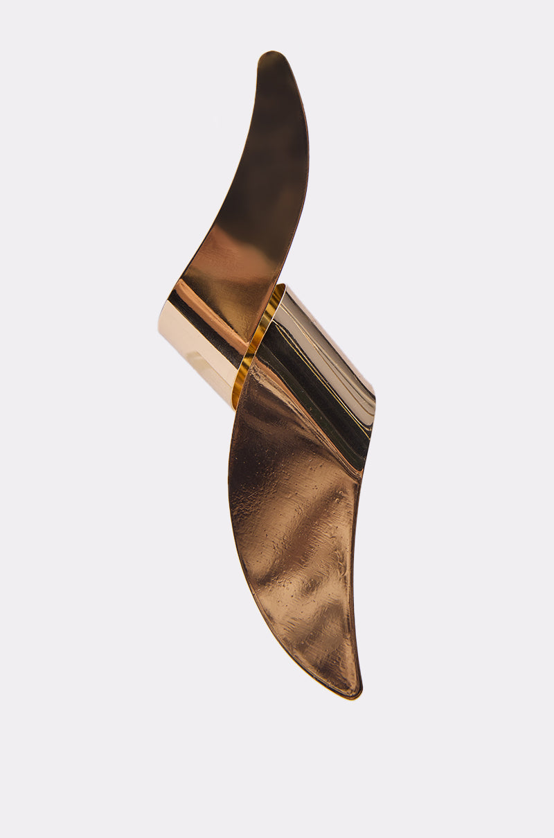 The TWISTED UP EARRING is a gold, abstract piece with two curved, wing-like extensions, evoking fluid sculptural lines, shown against a plain light background.