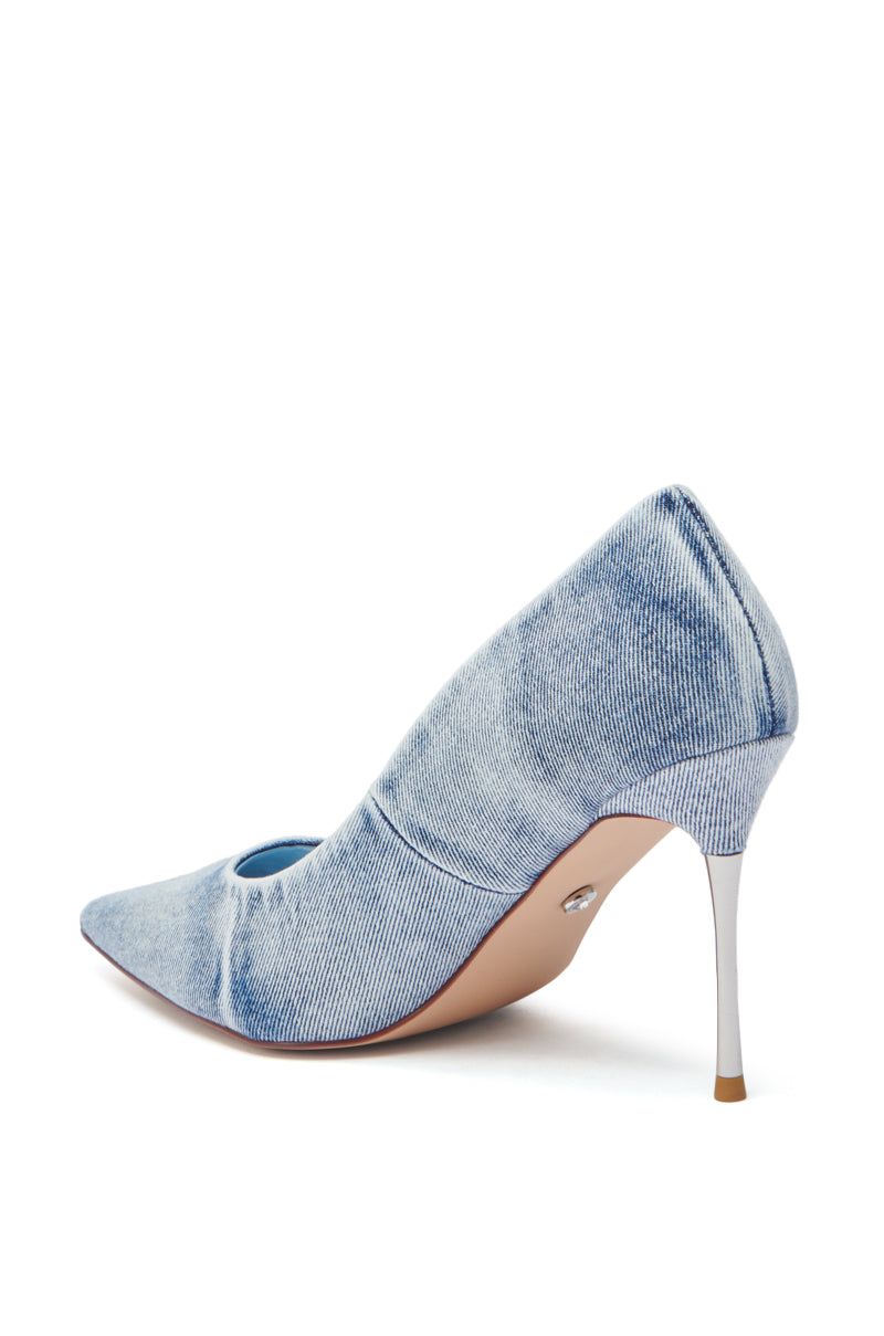 The AZALEA WANG KEATON DENIM STILETO PUMP is displayed from the side, showing its pointed toe, slim heel, and textured acid wash light blue denim finish against a white background.