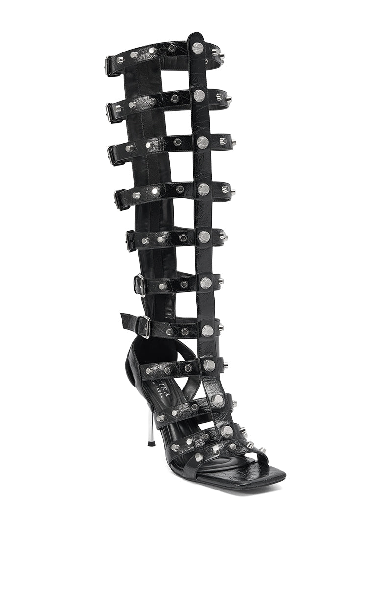 The AKIRA GOLD HARDWARE EMBELLISHED BLACK GLADIATOR SANDAL features multiple horizontal straps, gold hardware, silver studs, a stiletto heel, open toe, and knee-high design for a bold and edgy look. 4