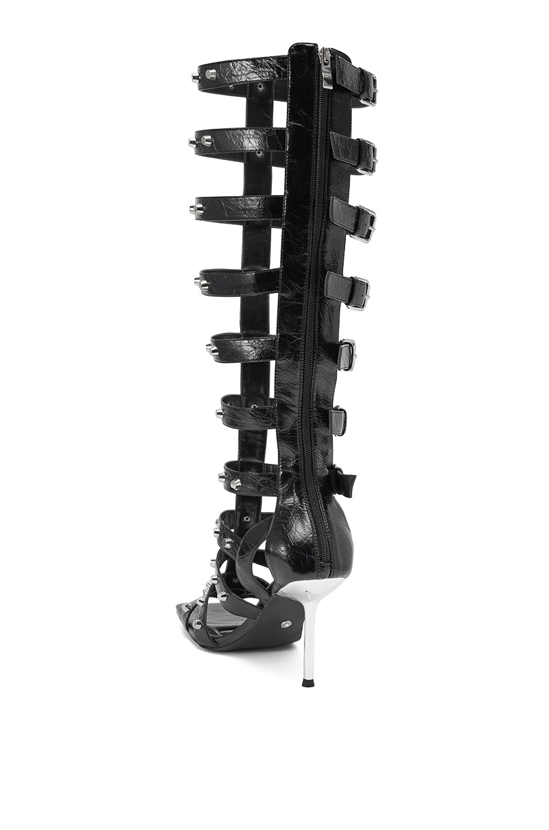 The AKIRA Gold Hardware Embellished Black Gladiator Sandal features a high heel, multiple black straps with gold hardware and buckles, a pointed stiletto heel, and a back zipper closure. 5