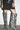 A person in a black dress with white speckles and AZALEA WANG KENYA ZEBRA KNEE HIGH WEDGE BOOTS stands against a white wall, hands resting on their thighs.