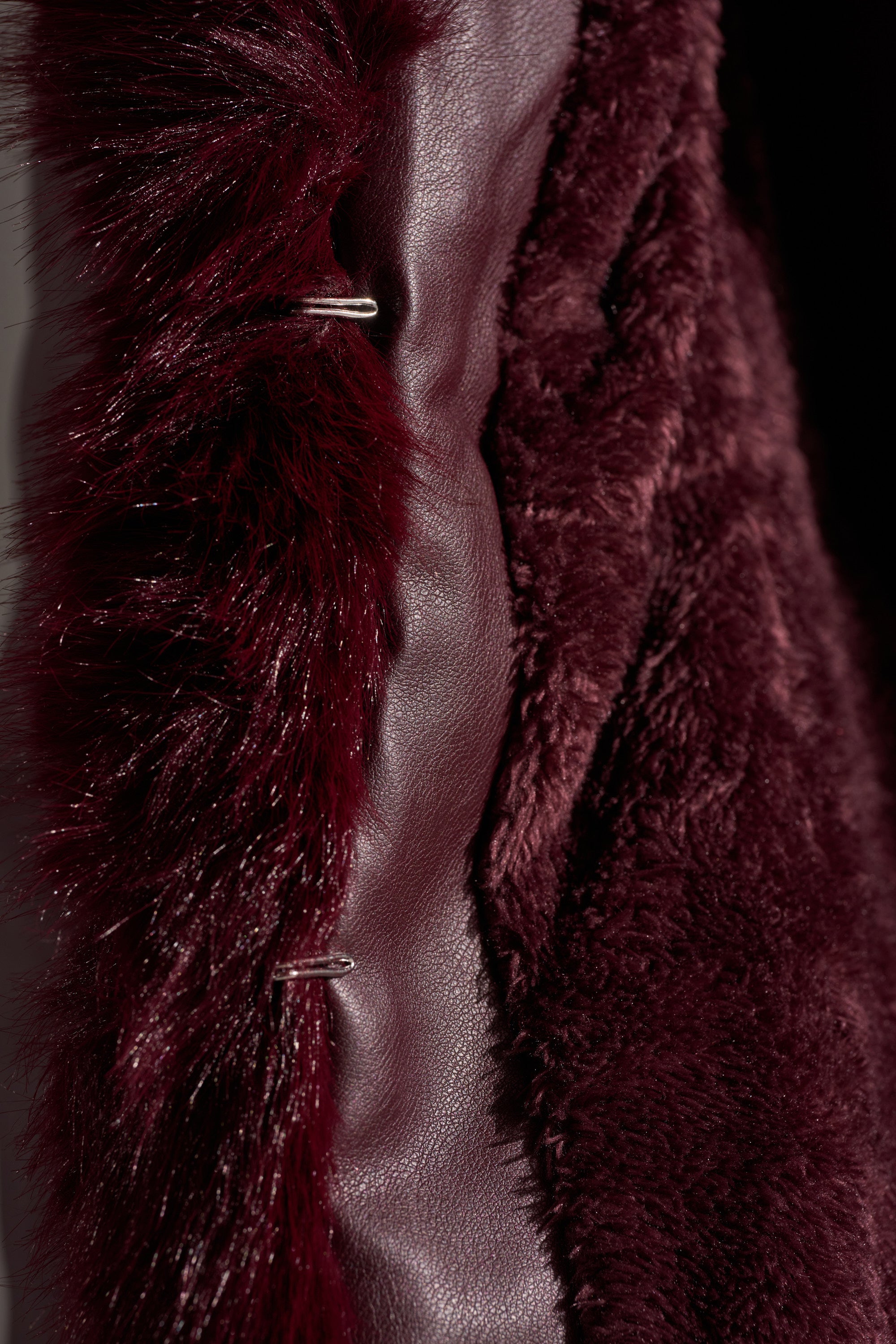 A close-up of the KENZY FUR TRIM MOTO IN BURGUNDY showcases plush faux fur, sleek faux leather accents, and a metal clasp—signature details of this chic moto jacket. 9