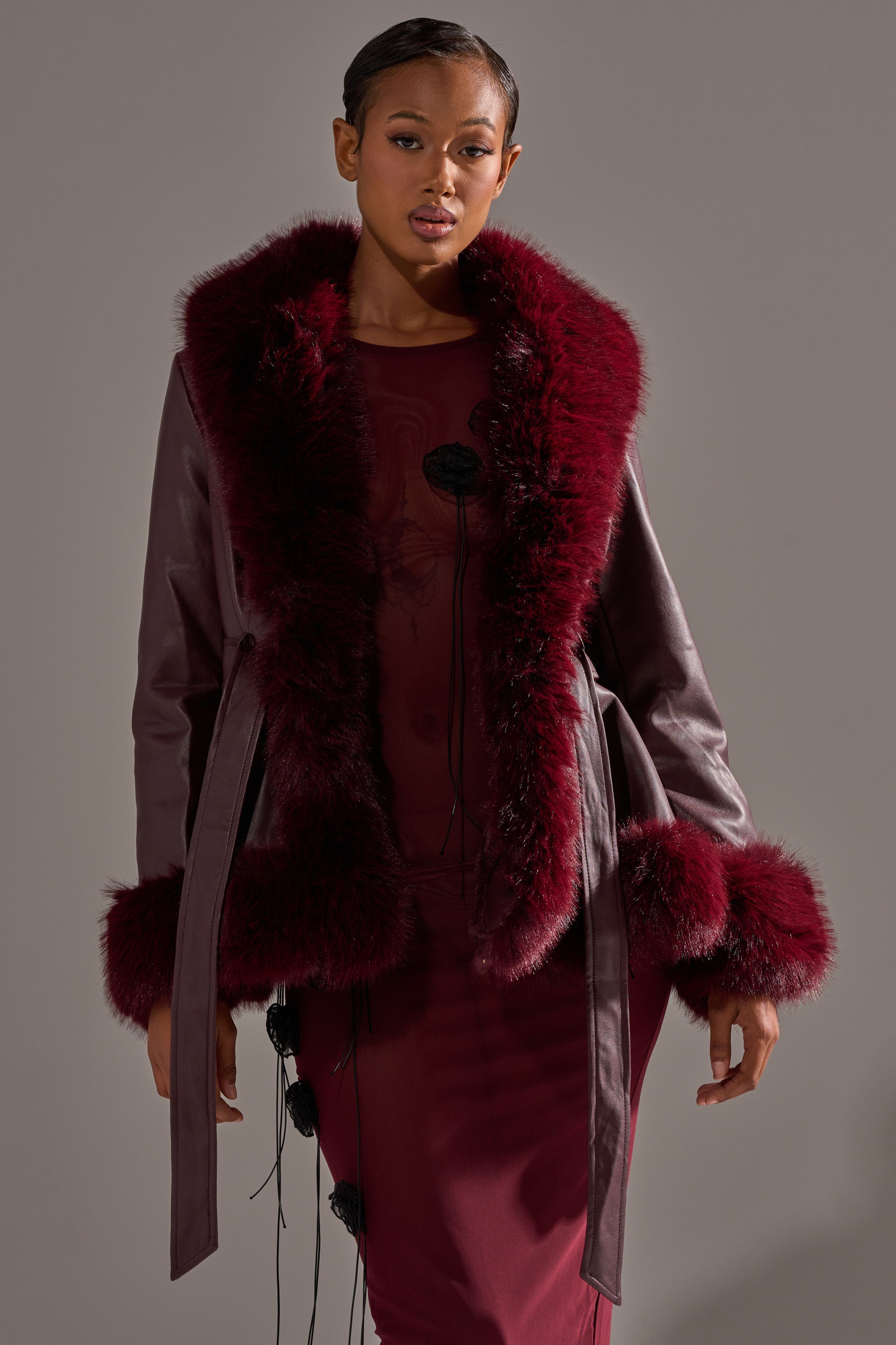 A woman models the KENZY FUR TRIM MOTO IN BURGUNDY, featuring chic faux fur trim, as she stands against a neutral background, gazing confidently at the camera with her hair styled back. 3