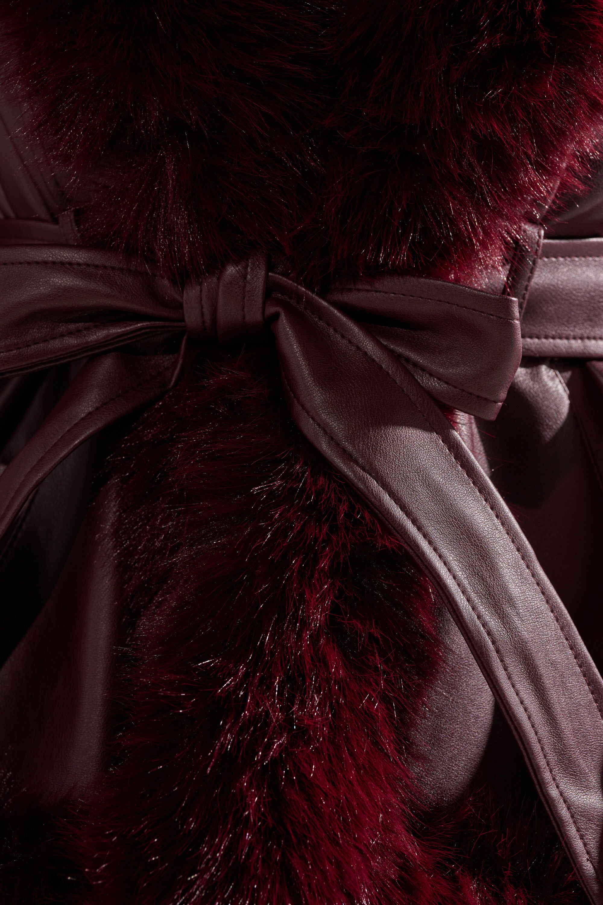 Close-up of the KENZY FUR TRIM MOTO IN BURGUNDY, featuring plush faux fur and a matching satin belt at the waist, showcasing its rich texture and luxurious feel. 7