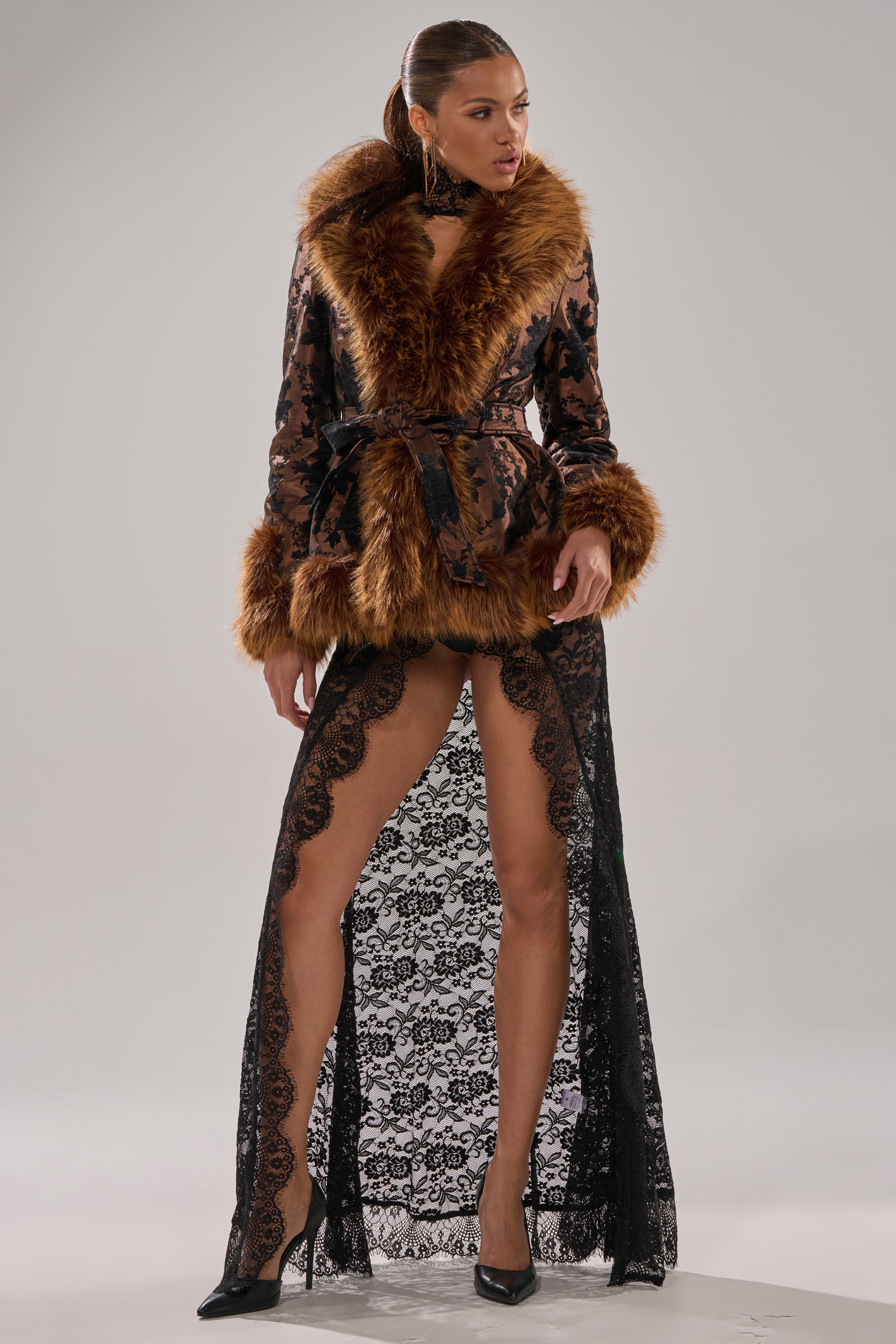 A woman models the KENZY FUR TRIM MOTO IN JACQUARD, featuring a leopard print with faux fur collar and black lace train, styled with black high heels against a plain backdrop.