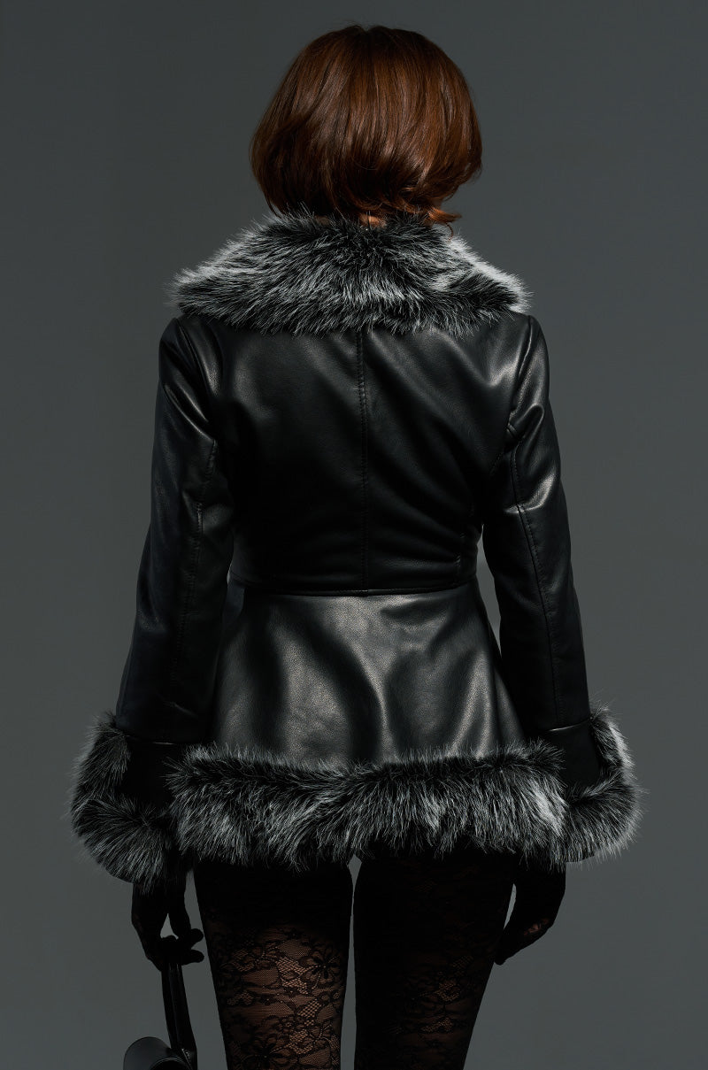 A person facing away, dressed in the NEW KENZY FUR TRIM MOTO jacket in black faux leather with gray fur trim on the collar, cuffs, and hem. The look is completed with black lace leggings and gloves, set against a plain gray background.