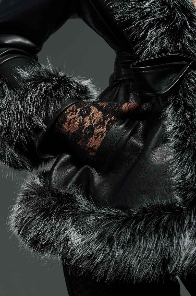 A person wearing the NEW KENZY FUR TRIM MOTO jacket with gray sherpa lining poses with their hand in a pocket. The hand is adorned with black lace gloves, adding a stylish touch to the luxurious outfit.