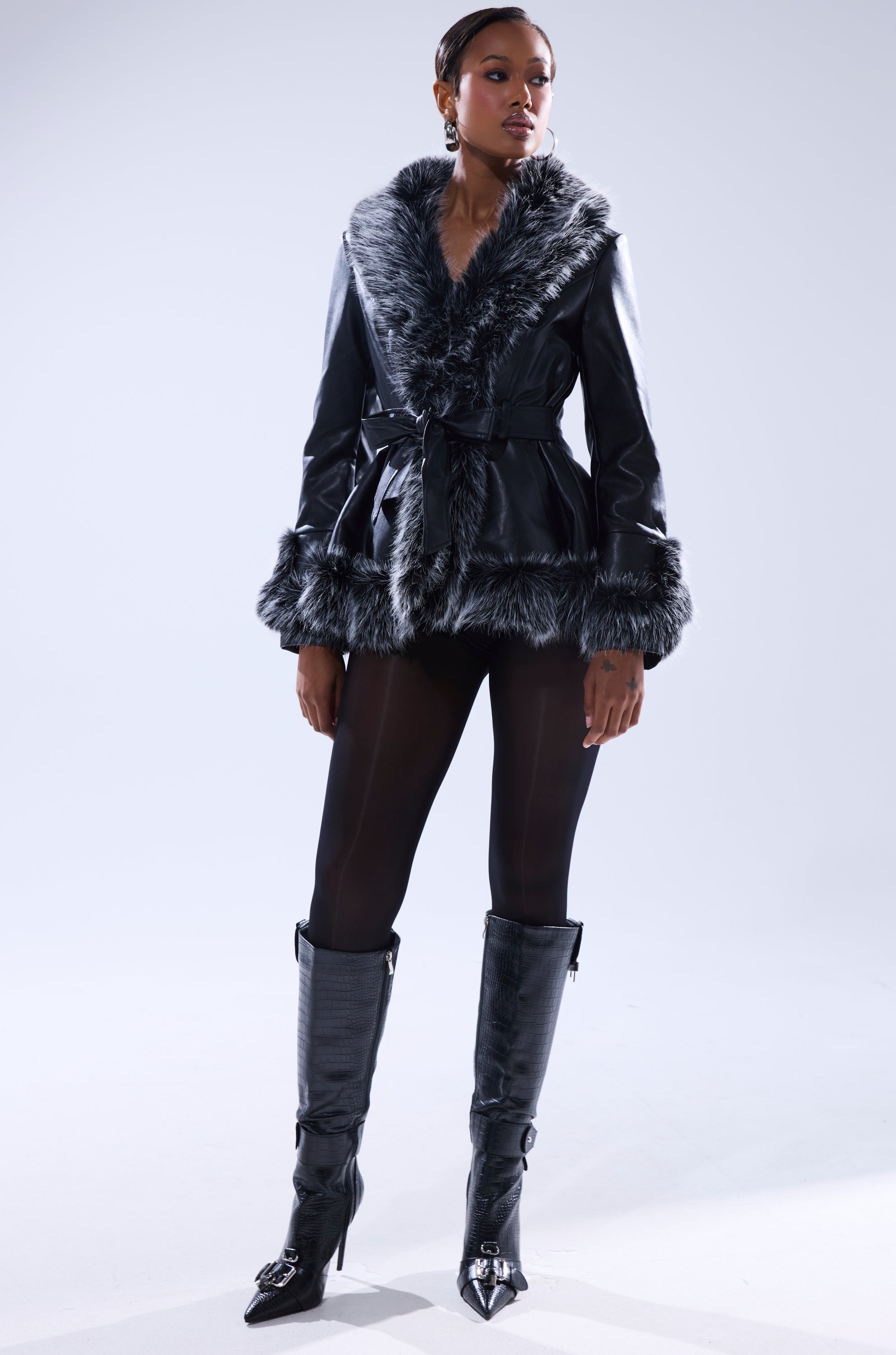 A woman stands confidently in the NEW KENZY FUR TRIM MOTO jacket, styled with black tights and knee-high boots against a plain light background.