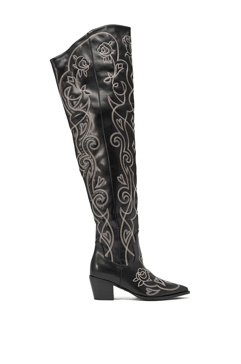 The AZALEA WANG KESS Black Western Thigh High Chunky Boot features black faux leather, a chunky heel, pointed toe, and detailed white floral and swirl embroidery on the shaft and foot. 5