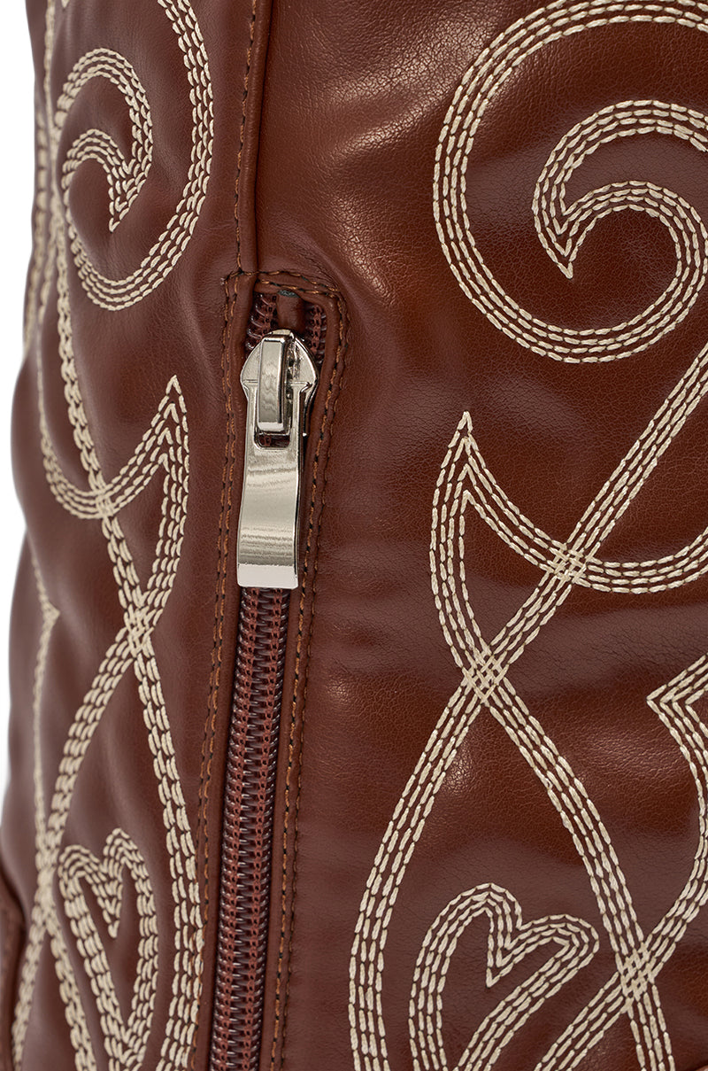 Close-up of the AZALEA WANG KETA BROWN WESTERN THIGH HIGH STILETO BOOT in brown faux leather, detailed with a silver zipper and swirling white embroidery. 6