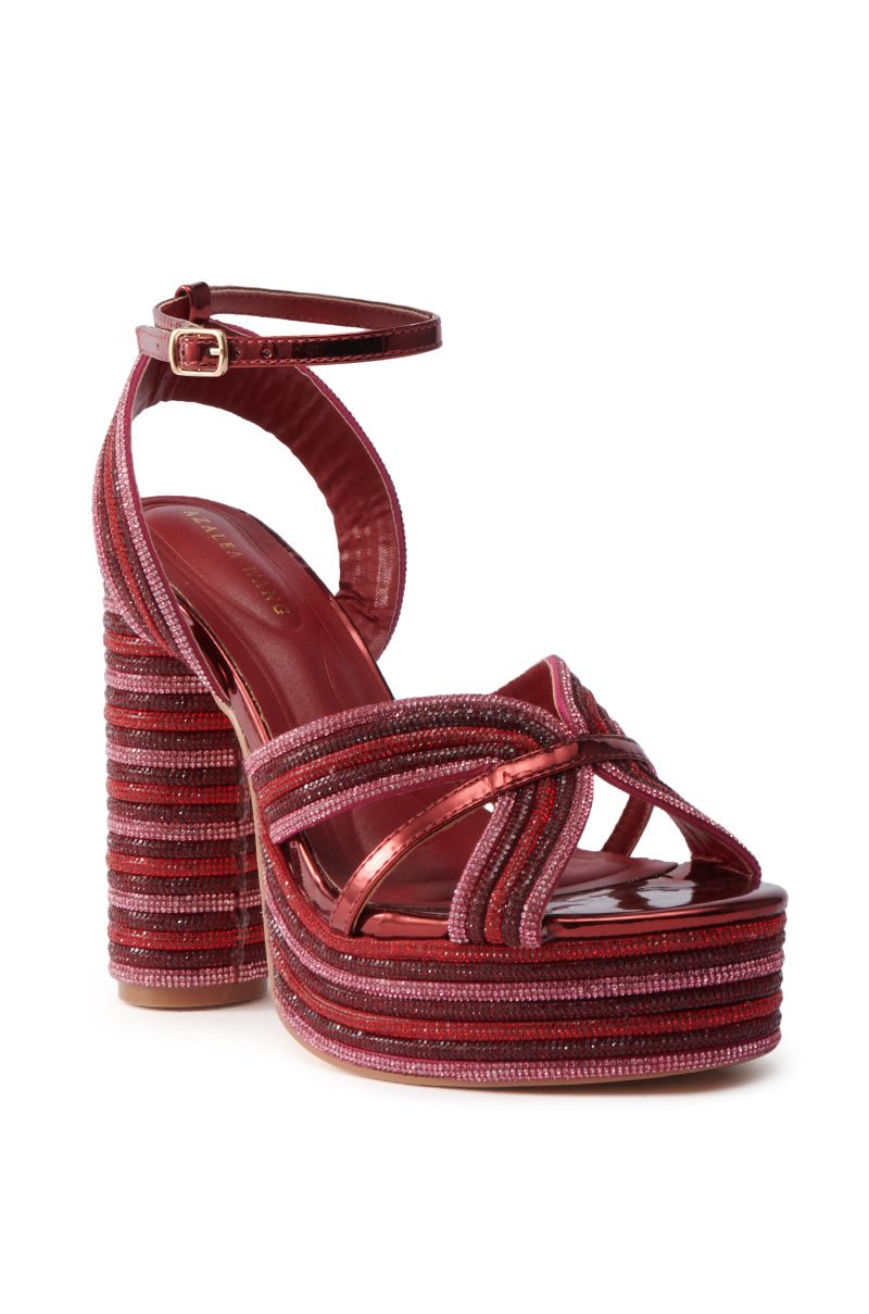 The AZALEA WANG KINSLEE BURGUNDY MULTI CHUNKY SANDAL features a thick platform and block heel, red and pink striped fabric, crisscross straps, rhinestone accents, and an ankle strap with a gold buckle for a stylish look.