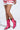 A person wearing a pink ruffled skirt stands against a light background in KITTY HOT PINK WESTERN BOOTIE, crafted from metallic faux leather with shiny pink chunky heels and a pointed toe for added flair.