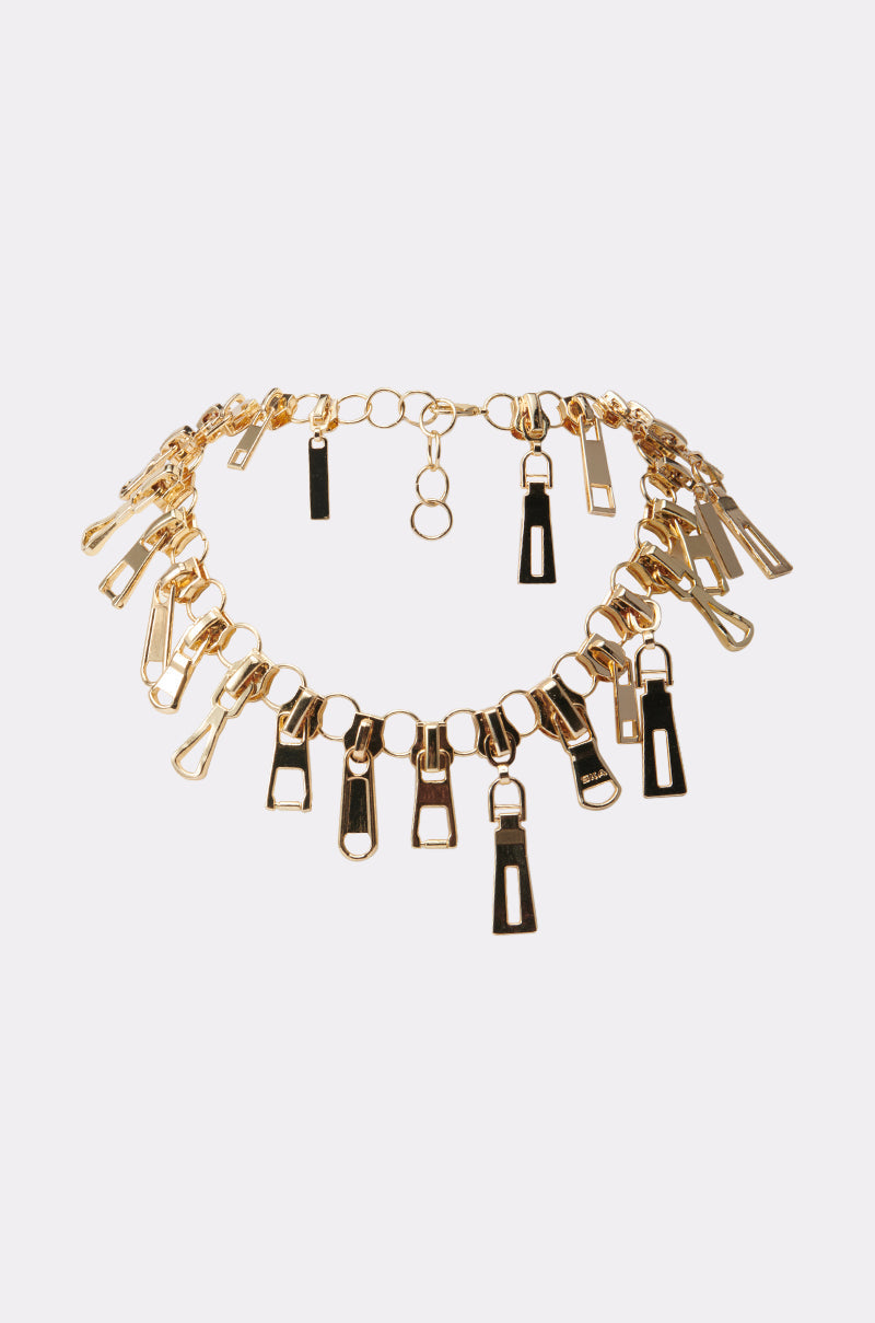 The ZIP IT NECKLACE features a chunky gold chain with evenly spaced metallic zipper pendants, shown on a simple white background. 0
