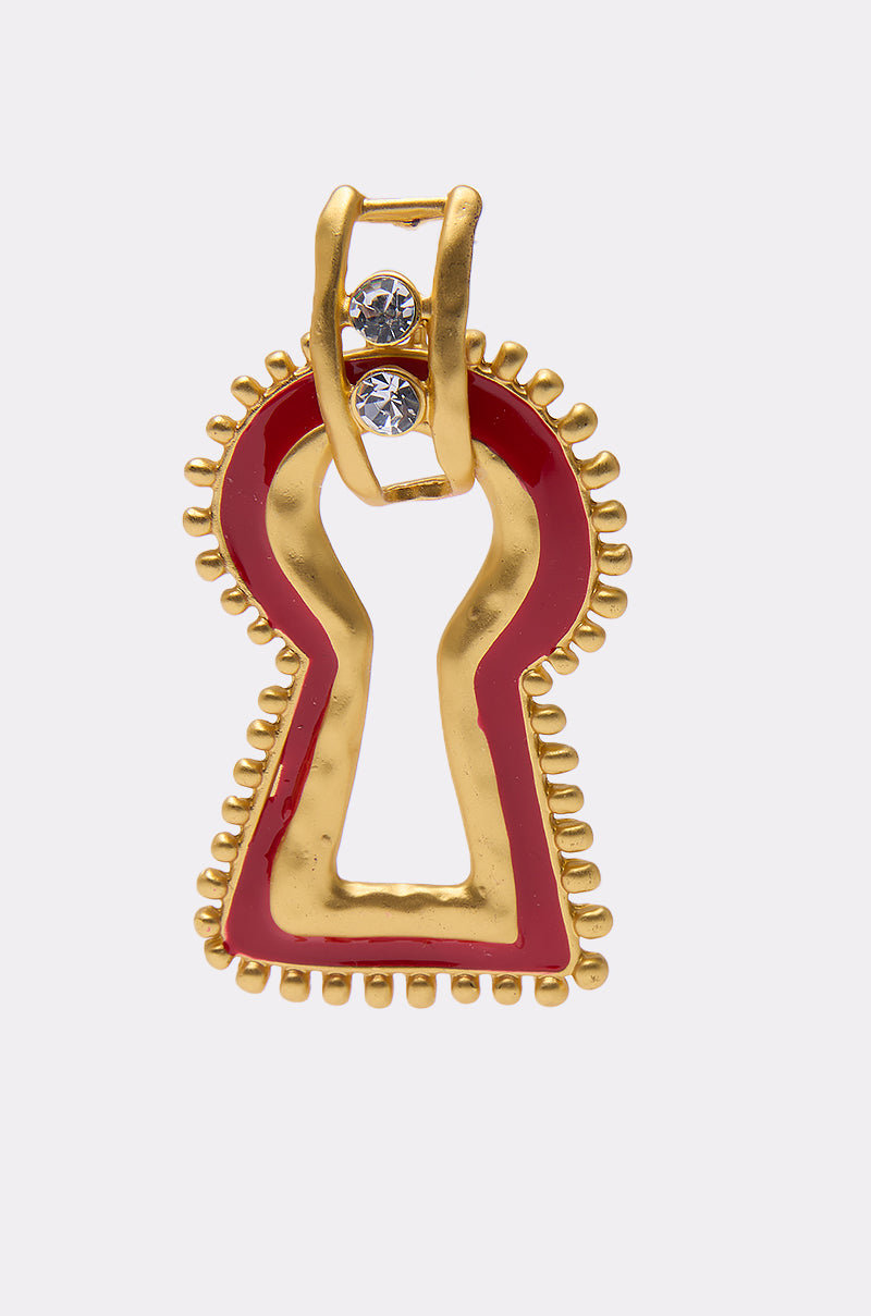 The UNLOCK ME EARRING features a gold keyhole-shaped design with a red enamel border, gold beaded detailing, and two small rhinestone accents at the top, displayed against a plain white background. 3