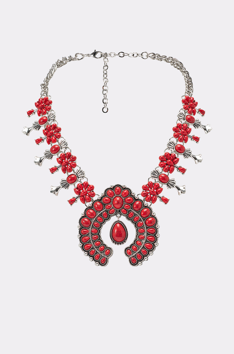 The TAKE ME OUT STONE NECKLACE is a silver chain statement piece with clustered red beads, floral shapes, and a bold ornate red stone pendant—ideal for fans of western-inspired jewelry. 1
